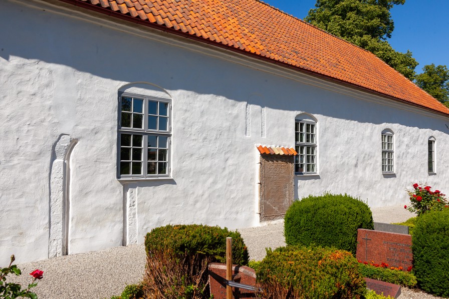 Den tilmurede syddør og et tilmuret romansk vindue. Herunder en gravsten fra 1766.